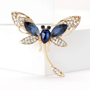 Macro shot of luxury dragonfly brooch with deep blue gems and white zircons on gold alloy