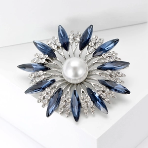 Close-up of elegant sunflower brooch featuring a large pearl center and blue gemstones