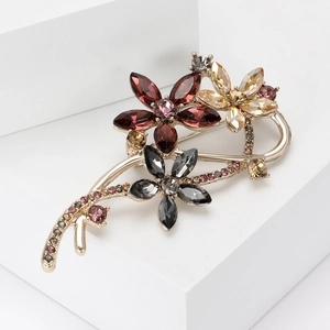 Vue détaillée d'une broche fleurie ornée de cristaux marquise rouges et champagne