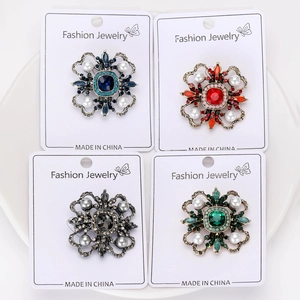 Detail view of four vintage baroque crystal flower brooches in assorted luxury colors