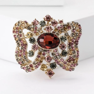 Macro view of vintage brooch featuring multi-color rhinestones and central red gemstone