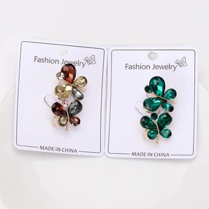 Détail de deux broches papillon avec cristaux ambrés et verts sur carte de mode