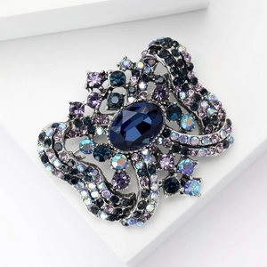 Detailed close-up of retro baroque brooch with oval blue crystal and colorful rhinestones