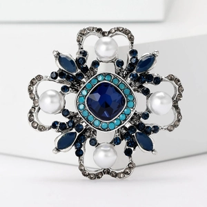 Detail of vintage Baroque brooch with blue crystals and white pearls on silver alloy
