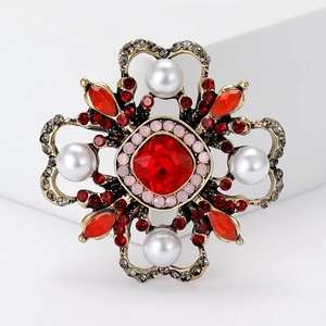 Close-up of Baroque vintage brooch with red crystal, pearls and antique gold finish