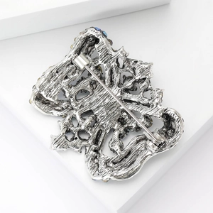 Macro view of the back of a vintage silver brooch with filigree patterns and safety pin