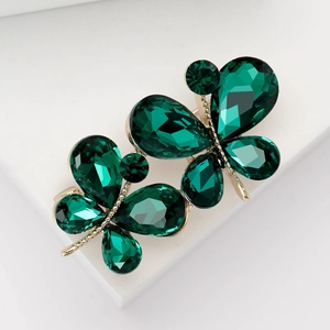 Broche papillon élégante vert émeraude avec plaquage or sur fond géométrique blanc