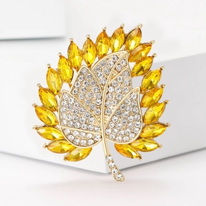 Makroaufnahme der goldenen Ahornblatt-Brosche mit gelben und weißen Strasssteinen