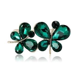 Broche papillon dorée élégante avec strass cristal émeraude sur fond blanc pur