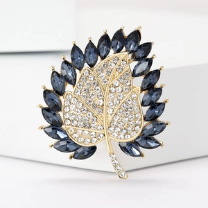 Eleganter Blatt-Brosche aus Gold mit weißen Kristallen und dunkelblauen Edelsteinen