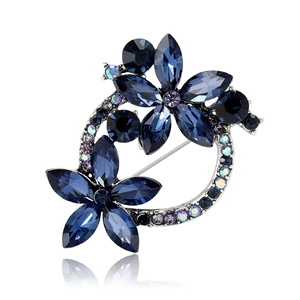 Elegant silver flower wreath brooch with deep blue and purple crystals on white background