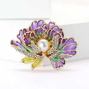 Détail de la broche pivoine en émail avec perle et cristaux sur un socle blanc épuré