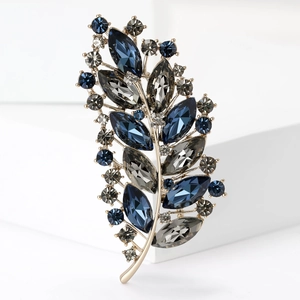 Detailed view of luxury leaf brooch with deep blue crystals and gold-tone alloy setting