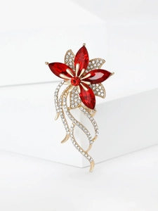 Dettaglio macro di spilla floreale vintage con strass rossi su base dorata e bianca