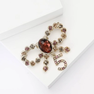Detailed shot of bow-shaped champagne gold brooch with rhinestones and number 5 pendant