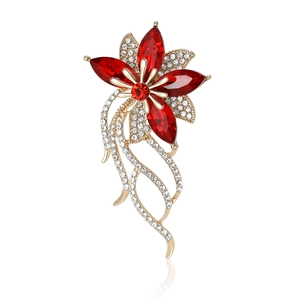 Spilla floreale elegante con cristalli rossi e nappe dorate su sfondo bianco per abiti donna