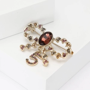 Elegant gold-tone ribbon brooch with red gemstone and crystal encrusted number 5 charm