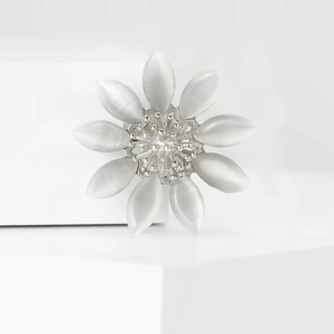 Détail d'une broche fleur argentée avec pétales en œil de chat et pistils texturés
