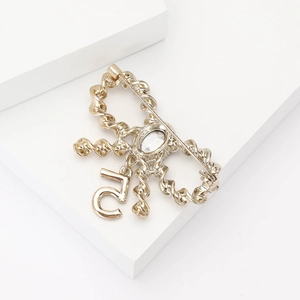 Detailed close-up of a golden rope-textured brooch with an oval gem and number 5 pendant