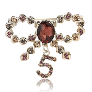 Exquisite bow brooch with red oval gemstone and rhinestone number 5 charm on white background