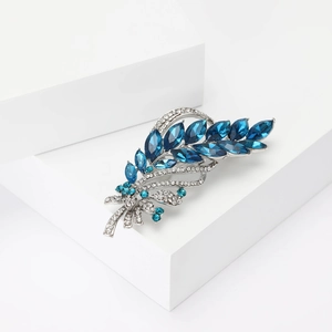 Eleganter Weizenähren-Brosche mit tiefblauen Kristallen auf weißen Geometrie-Blöcken