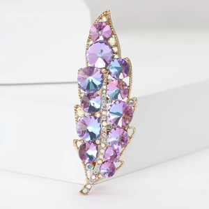 Spilla a foglia dorata con cristalli viola e blu su supporto geometrico bianco