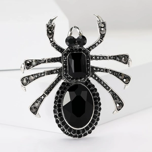 Détail macro d'une broche araignée gothique avec cristaux noirs et métal argenté