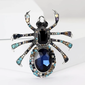 Broche araignée exagérée avec cristaux bleus et strass colorés sur fond blanc pur