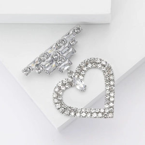 Dettaglio della spilla a cuore in argento con pavé di cristalli su piedistallo bianco