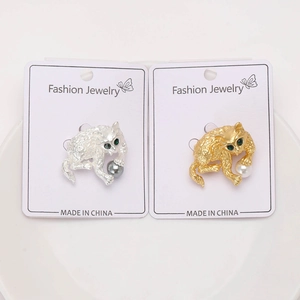 Detail van zilveren en gouden kattenbroches met groene strass-ogen op displaykaarten