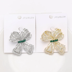 Close-up of bow brooches with micro-pave zircons and emerald green center stones