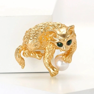 Prachtige gouden kattenbroche met witte parel en groene edelsteenogen op standaard
