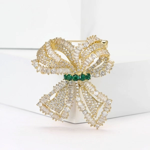 Elegant bow-knot brooch with micro-set zircons and emerald-green gems on gold base