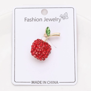 Détail de la broche cerise scintillante avec cristaux rouges et feuilles vertes