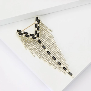 Dettaglio di elegante spilla a Y con pietre nere e nappe di diamanti scintillanti per abiti