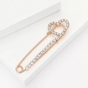 Broche cœur élégante avec strass en finition or rose sur un support blanc minimaliste