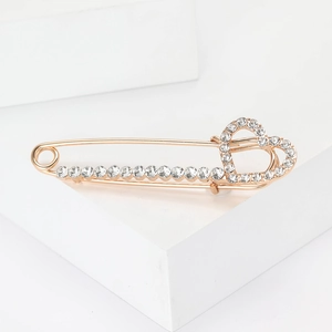 Élégante broche épingle de sûreté cœur doré avec strass sur un socle blanc
