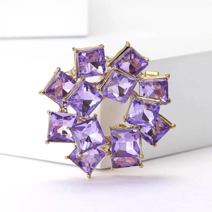 Elegant gold flower brooch with square cut purple crystals on a geometric podium