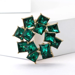 Close-up of green crystal square stones set in a gold double-layered brooch ring