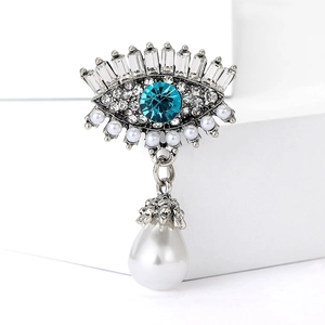 Détail macro de la broche œil avec cristal bleu et grand pendentif en perle goutte