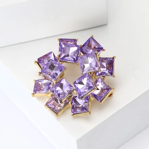 Elegant gold double-layered brooch with purple square-cut crystals on white geometric block