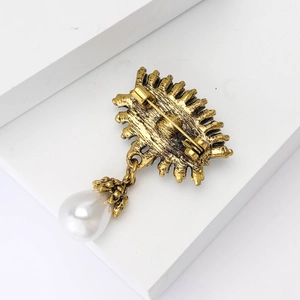 Vue arrière détaillée d'une broche œil vintage dorée montrant le fermoir et la perle