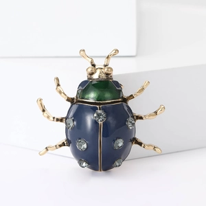 Détail de la broche coccinelle en émail bleu avec finition dorée et strass