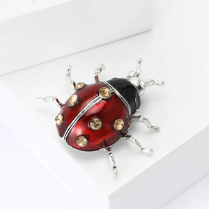 Broche coccinelle chic avec ailes en émail rouge et cristaux sur un présentoir