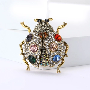 Vue macro d'une broche scarabée avec cristaux colorés et strass blancs sur alliage doré