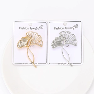 Detailed close-up of gold and silver ginkgo leaf brooches with sparkling white rhinestones