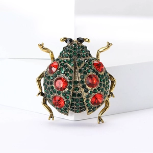 Vue détaillée de la broche coccinelle ornée de cristaux verts et strass rouges