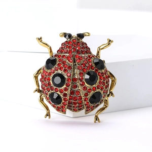Broche coccinelle élégante avec cristaux rouges et pierres noires sur base dorée