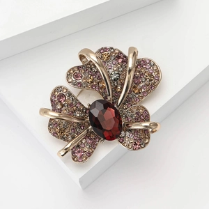 Macro detail of vintage fleur-de-lis brooch with red crystal and sparkling rhinestones