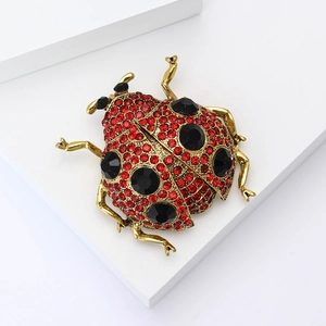 Élégante broche coccinelle dorée avec cristaux rouges et accents de strass noirs